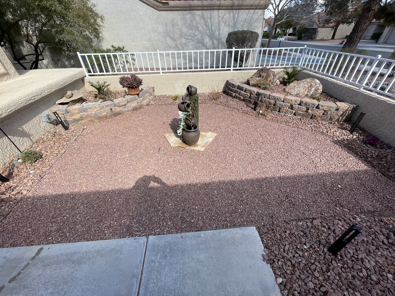 Desert backyard with decorative gravel, tiered stone planters and fountain