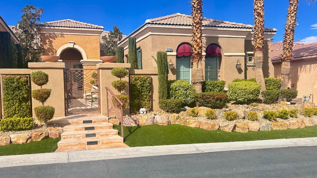 Front yard with manicured topiary, artificial turf, rock landscaping and stone steps